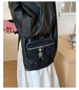 Detail of black crossbody bag with metal robot charm and mixed suede leather texture