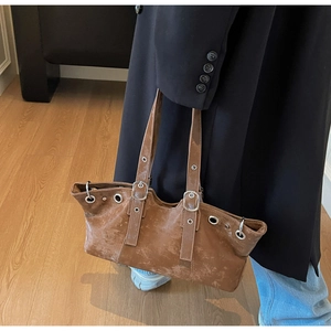 Detail of vintage brown leather tote bag with metallic eyelets and adjustable strap