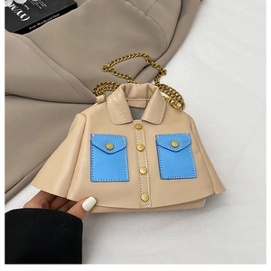 Close-up of jacket-shaped chain bag featuring beige leather and blue pocket detailing