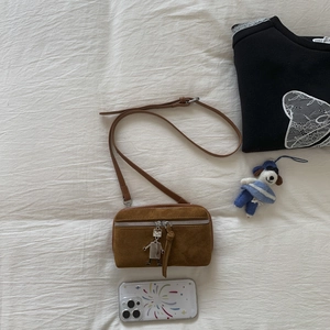 Detailed view of brown suede crossbody bag featuring a unique silver robot zipper charm