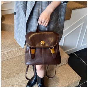 Detail of vintage dark brown PU leather backpack featuring golden twist lock hardware