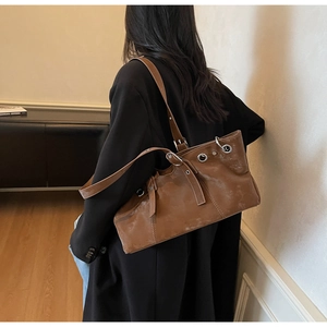 Détail du sac cabas marron montrant le similicuir lisse et les œillets métalliques