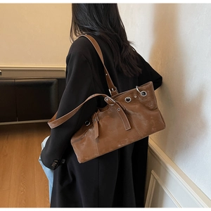 Détail du cabas vintage en cuir marron avec œillets et bandoulière réglable sur modèle