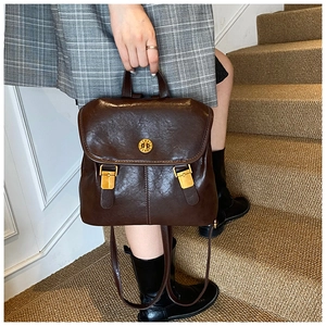 Detail view of a vintage dark brown PU leather backpack with gold metal twist lock buckle