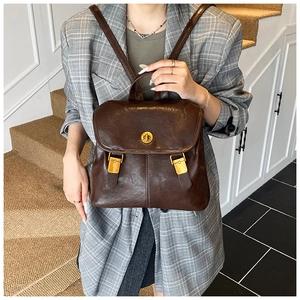 Detail of vintage brown leather backpack showing rotating gold lock and top handle grip