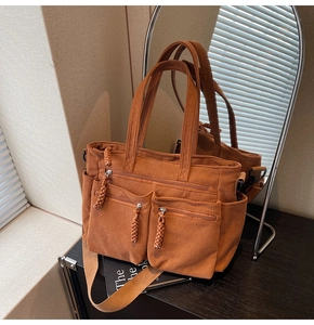 Detailed view of caramel corduroy tote bag showing multiple front zipper pockets and texture
