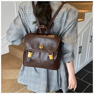 Detail of vintage brown PU leather backpack featuring a gold swivel lock and retro texture