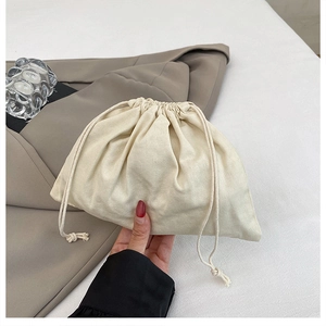 Detail of cream-colored drawstring bucket bag in soft fabric with elegant pleats
