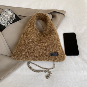 Brown fuzzy triangle handbag with metal chain strap and brand label on fabric background