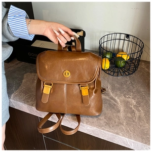 Close-up of brown vintage PU leather backpack with golden buckle on marble surface
