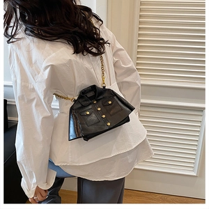 Detail of creative black leather jacket shaped crossbody bag with gold chain strap