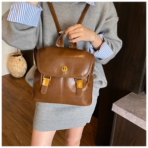 Detailed view of brown vintage leather backpack featuring golden twist lock and flap