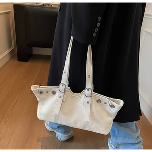 Detail of cream leather handbag with silver eyelets and adjustable buckle shoulder strap