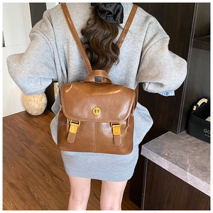 Brown PU leather backpack with gold buckle and top handle shown on a model's back