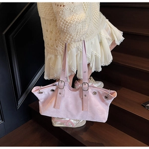 Détail du cabas en faux daim rose avec œillets métalliques sur un escalier en bois