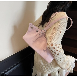 Détail d'un sac à bandoulière en cuir rose clair avec œillets argentés et boucle réglable