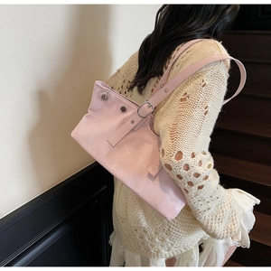 Detail view of pink leather shoulder bag with silver metal eyelets and adjustable strap