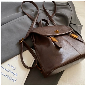 Detail of dark brown vintage PU leather backpack with gold buckle and smooth texture