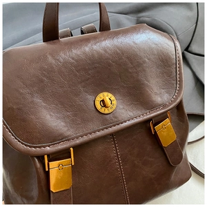 Close-up of vintage dark brown PU leather backpack with gold Roman numeral twist lock