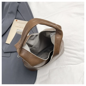 Vista detallada del bolso saco de cuero marrón con forro de espiga gris y bolsillo interior