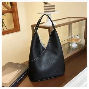 Detalle de un bolso de hombro asimétrico de cuero negro mate en estilo de café