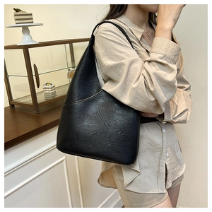 Primer plano de un bolso tipo cubo de cuero retro negro con textura llevado al hombro