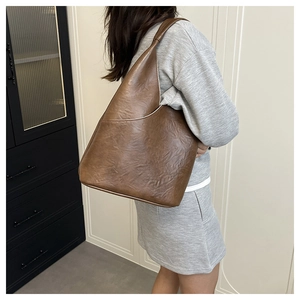 Bolso de hombro grande marrón en piel sobre modelo mostrando textura suave y caída