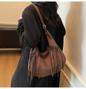 Détail d'un sac cabas en daim marron avec de longues franges et boucle en métal