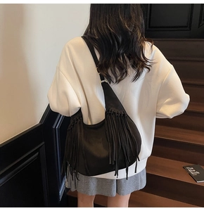 Détail du sac hobo en daim noir avec de longues franges et des ferrures dorées