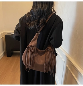 Détail d'un sac à bandoulière en daim marron foncé avec franges de style sur un mannequin