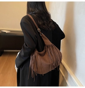 Sac hobo en daim marron avec longues franges et bandoulière réglable porté par un mannequin