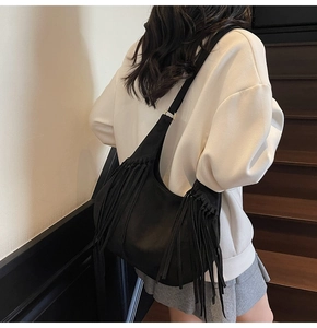 Vue détaillée du sac à bandoulière en daim noir avec franges et anneaux dorés