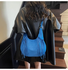 Sac hobo bleu en daim avec franges longues et anneaux dorés porté par un mannequin