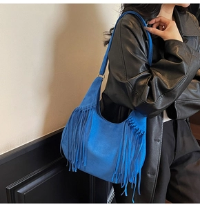 Détail du sac Hobo bleu Klein avec texture en daim et longues franges sur un modèle