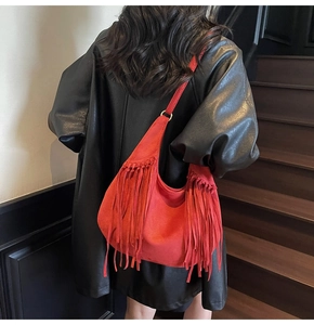 Vue détaillée d'un sac bandoulière rouge en daim avec de longues franges et boucles en métal