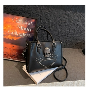 Détail d'un cabas punk avec un grand crâne en strass et des clous argentés sur cuir noir