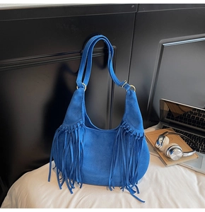 Détail du sac hobo en daim bleu avec de longues franges et une boucle dorée