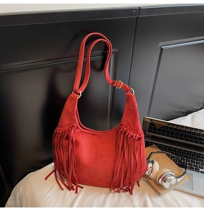 Détail d'un sac hobo en daim rouge avec longues franges et boucle en métal doré