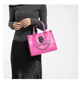 Detail of hot pink tote bag featuring a skull ornament and metal rivets in goth style