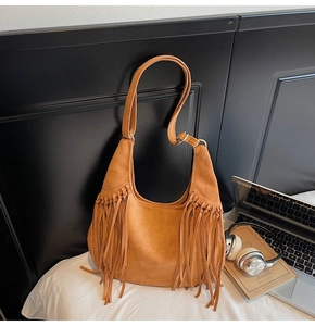 Gros plan d'un sac hobo en daim marron avec de longues franges et boucle dorée