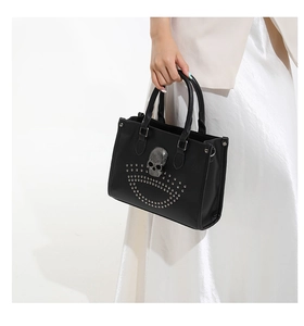 Détail du sac punk noir avec emblème de crâne argenté et décoration de rivets en métal