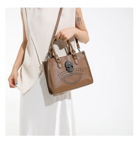 Macro detail of brown leather tote bag with metallic skull and silver rivets