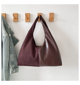 Detail of burgundy tote bag showing suede and smooth leather texture contrast on a hook