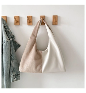 Close-up of two-tone shoulder bag with beige suede and white leather patchwork design