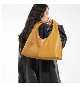 Detail of the oversized patchwork hobo bag in mustard suede and leather on model