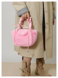 Detail of pink faux fur handbag featuring pleated handle and drawstring bow decoration