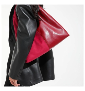 Detail view of red patchwork leather shoulder bag showing contrast of glossy and matte textures
