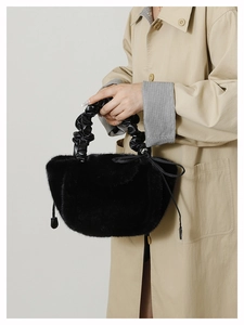 Detail of black faux fur handbag with stylish ruched leather handle and side ties
