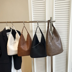 Bolsos tipo cubo retro de cuero sintético en cuatro colores colgados en soporte