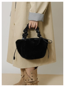 Detail of black plush handbag featuring ruched leather handle and drawstring sides